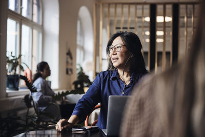 Businesswoman talking through wired headphones at coworking office