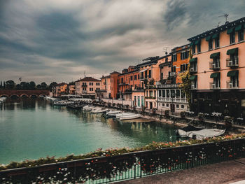 Canal amidst buildings in city against sky