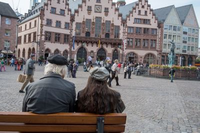 Rear view of people sitting in front of buildings