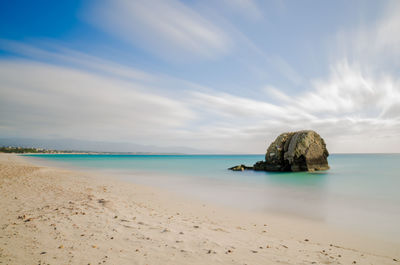 Scenic view of beach against cloudy sky