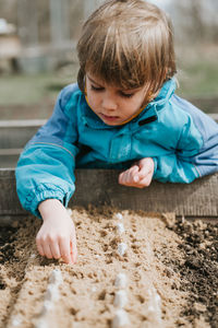 Spring planting seeding farm garden. little kid boy farmer gardener plants sow vegetable seeds soil