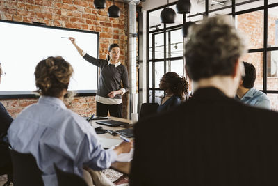 Mature businesswoman giving presentation to male and female colleagues in board room