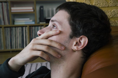 Side view of sad man crying with hand covering mouth at home