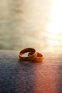 Close-up of wedding rings in front of sea during sunset