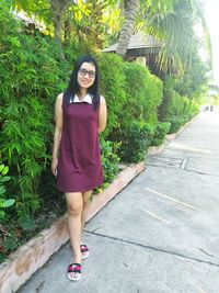 Portrait of smiling young woman standing by plants