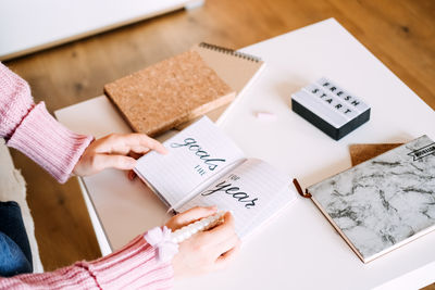 Midsection of woman writing on book
