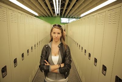 Portrait of serious young woman with arms crossed standing in locker room