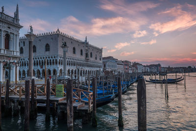 Mooring post of gondolas in venice with palace of the doges at sunrise.