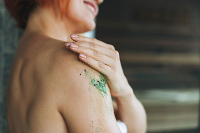 Young woman in white towel does body massage with organic natural scrab in bath, treat yourself