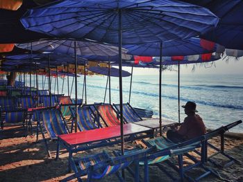 Rear view of man sitting on seat at beach