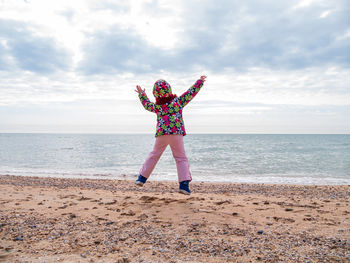 Little girl jumping on empty beach flying in the air lifestyle people scenic landscape active family