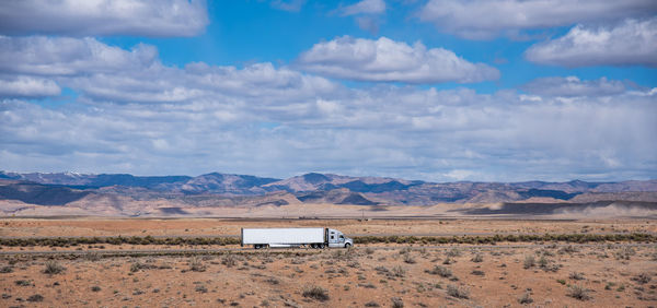 Scenic view of field against sky and truck on highway