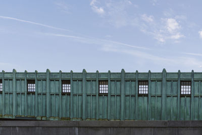 Part of elevated station in boston. green metal wall exterior of a train platform