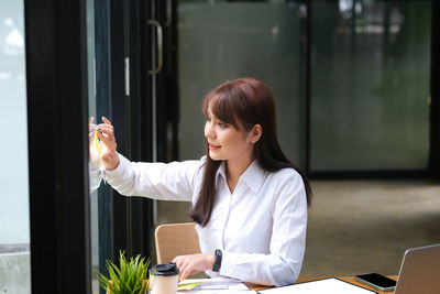 Young woman playing with leaf while sitting in office