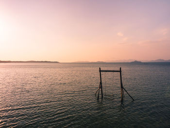 Scenic sea view with sunset orange sky with lonely wooden swing. koh mak island, trat, thailand.