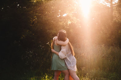 Lesbian couple embracing in forest during summer