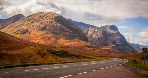 Road by mountains against sky