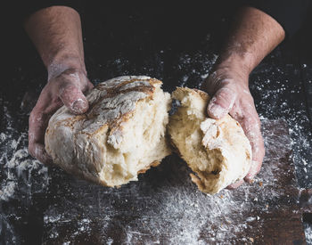 Close-up of person breaking bread at counter