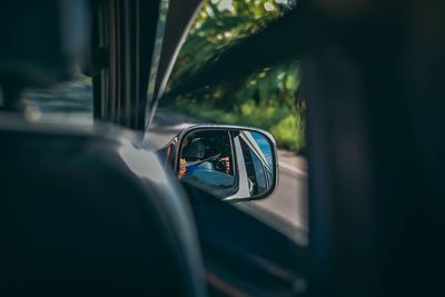 Reflection of man on side-view mirror