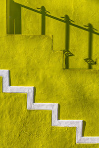 Shadow of railing on yellow wall