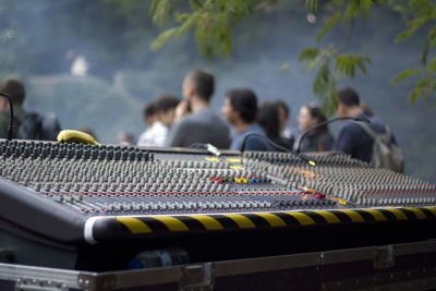 Close-up of sound mixer with people standing in background