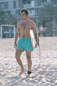 Shirtless man with surfboard at beach