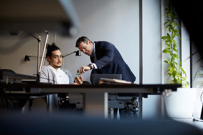 Creative businessman discussing with bank manager over solar toy car in creative office