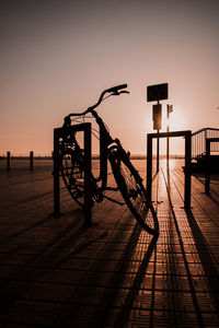 Silhouette of bicycle parked on street against sky