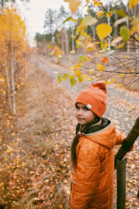 Girl in orange coat walks in fall forest. thinking, mental health. autumn vibes. outdoor lifestyle