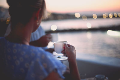 Man holding coffee cup against sky