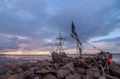 Shipwreck on beach against sky during sunset