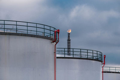 Low angle view of petrol silos against sky