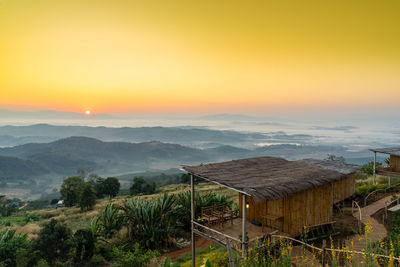 Scenic view of landscape and houses against sky during sunset