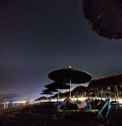 Parasols on beach against sky at night