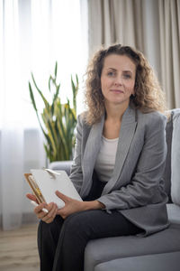 Portrait of young woman using laptop while sitting on sofa at home