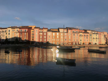 Boats moored in canal by buildings against sky in city