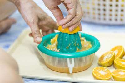 Cropped hands squeezing orange