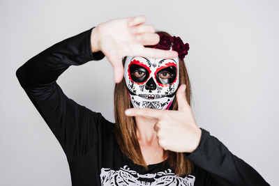 Portrait of beautiful young woman holding hat against white background