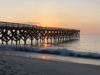 Pier over sea against sky during sunset