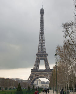 Communications tower in city against cloudy sky