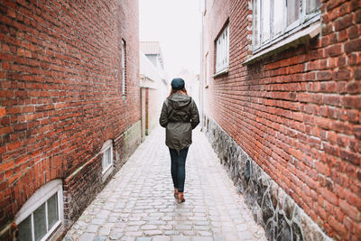 Full length of woman walking in alley amidst buildings
