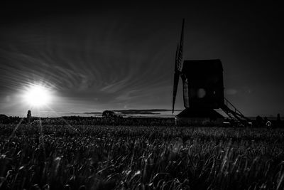 Traditional windmill on field against sky at sunset