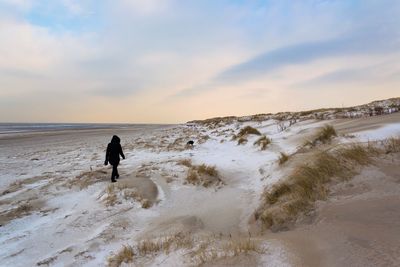 Silhouette man walking on beach against sky