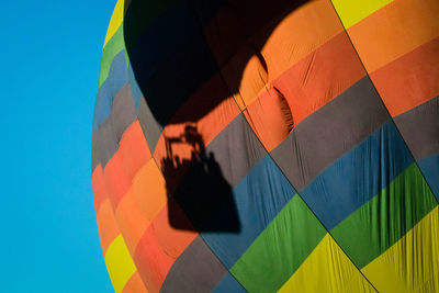 Shadow on hot air balloon flying against clear blue sky