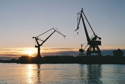 Scenic view of sea against sky during sunset, industrial harbour with cranes