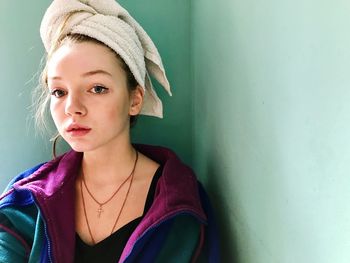 Portrait of beautiful young woman standing against wall