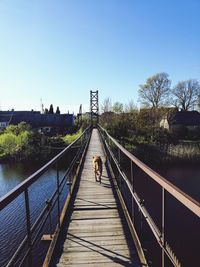 Footbridge over canal against clear sky