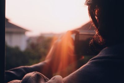 Rear view of woman sitting against orange sky