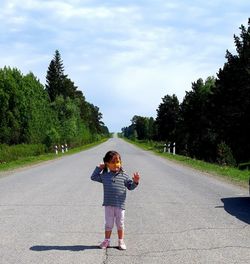 Full growth of a child standing on the road opposite the sky