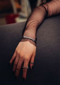 Cropped hand of woman wearing jewelry on sofa